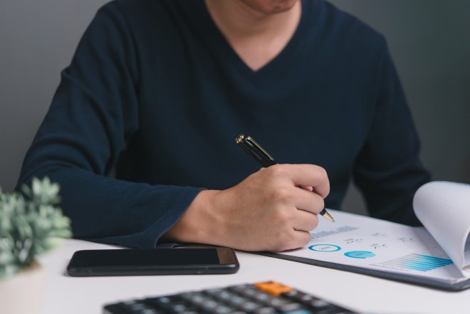 A business professional reviews analytical reports with, pen in hand