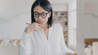 Businesswoman in glasses counts profit on calculator, analyzes company budget. Financial management