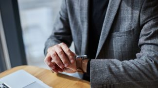 Close-up businessman in formal suit, checks the time on his wristwatch. Time management. Punctuality