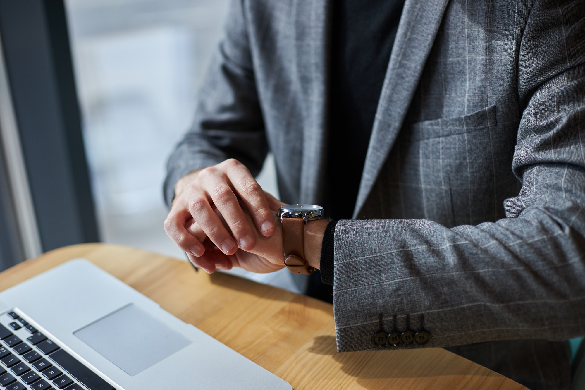 Close-up businessman in formal suit, checks the time on his wristwatch. Time management. Punctuality