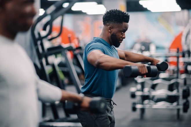 Determined male athlete lifting dumbbells during fitness training in gym