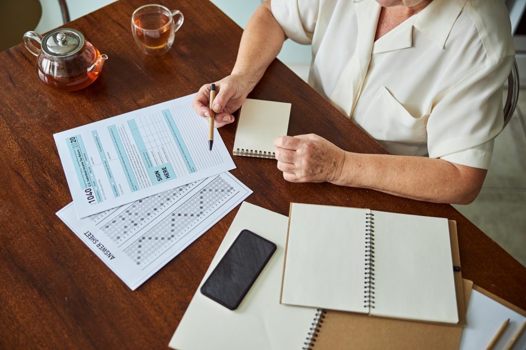 Elderly woman filling out taxes form at home