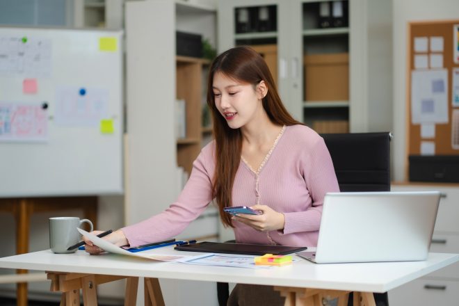 Female coder or developer working using a computer display and smartphone