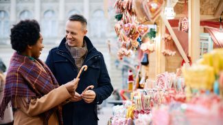 Happy couple buying candy cane on Christmas market.