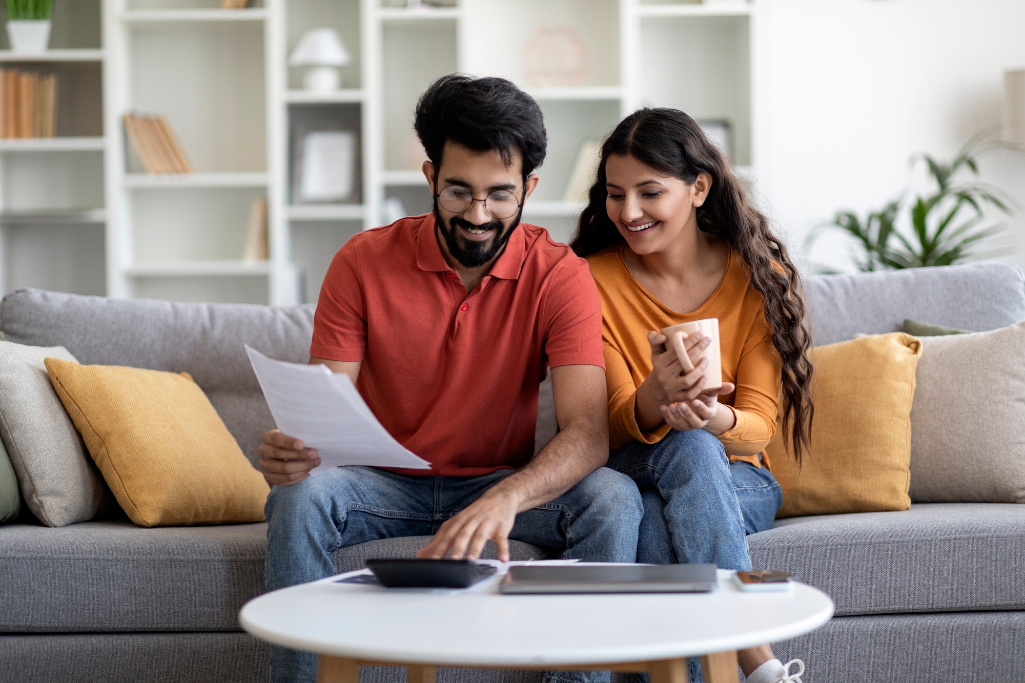 Indian Married Couple Planning Budget Together, Reading Papers And Calculating Spends