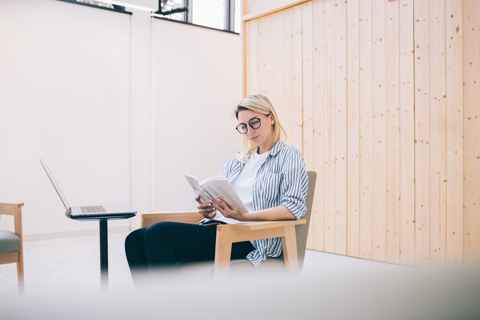 intelligent woman in classic glasses reading tutorial book during distance work