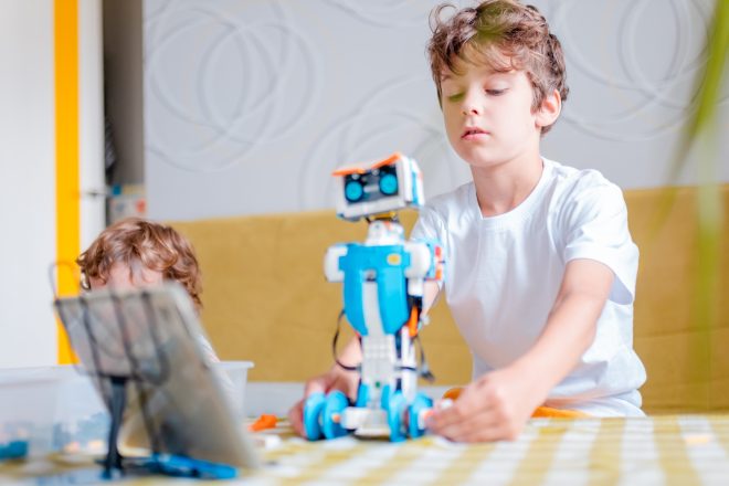 Kid programming robot from plastics details and programmed on tablet, robotics.