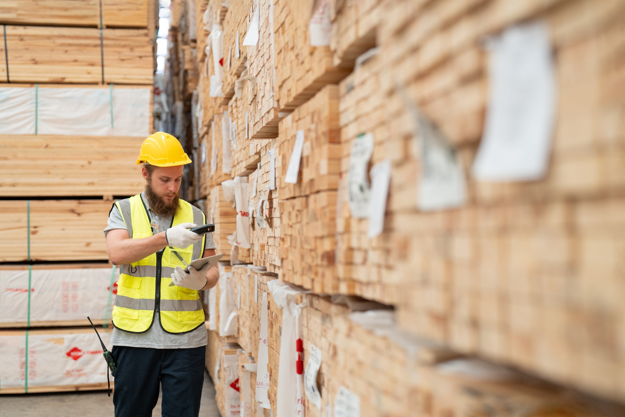 Male worker using scanner machine scanning barcode on label checking plank wood stock at warehouse