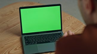 Man video calling greenscreen laptop gesturing home closeup. Businessman talking