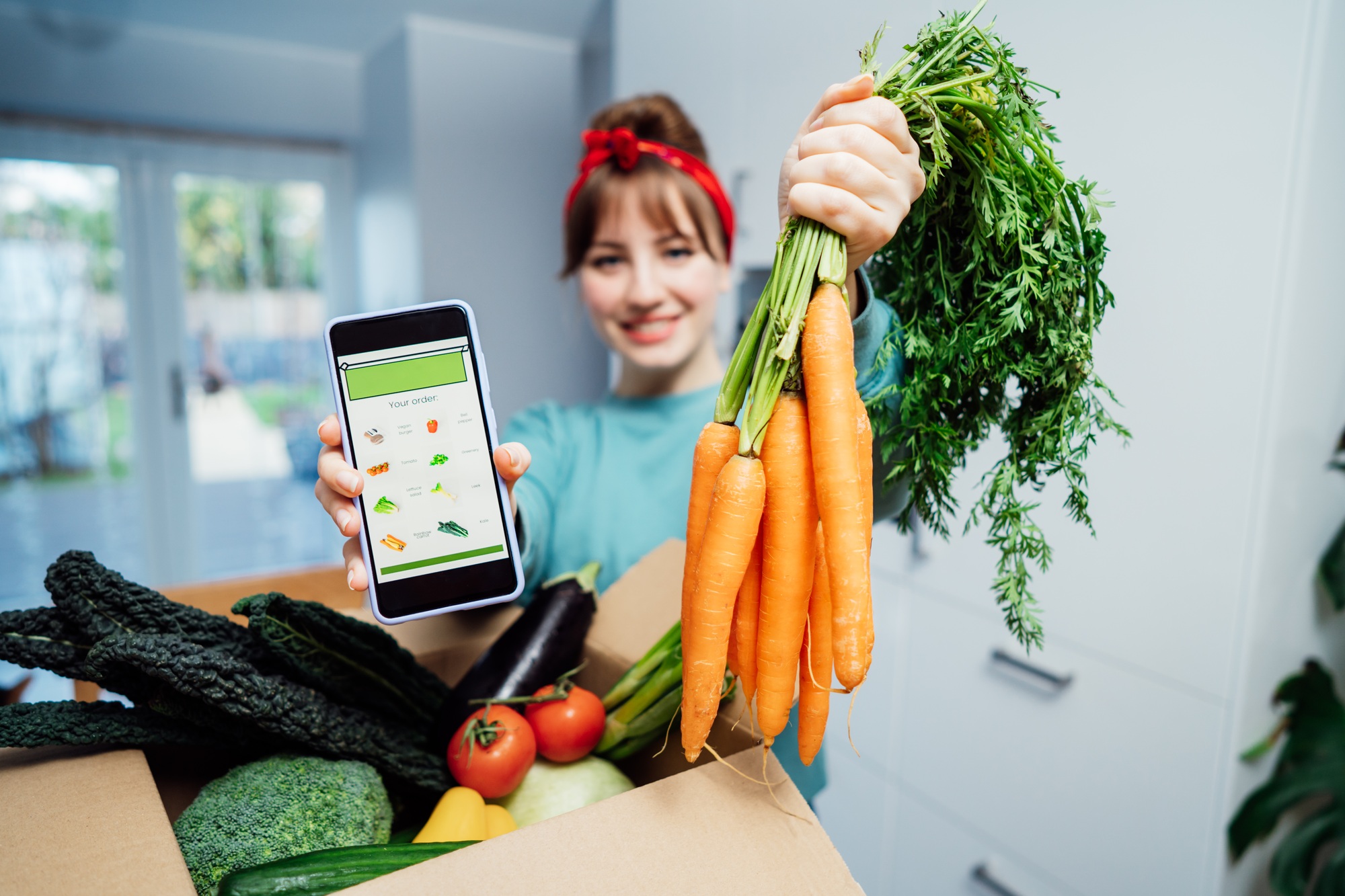 Online home food delivery. Focus on active app with order list on the phone screen and carrot bunch