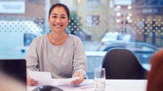 Portrait Of Smiling Asian Businesswoman Sitting At Table In Office Meeting Room