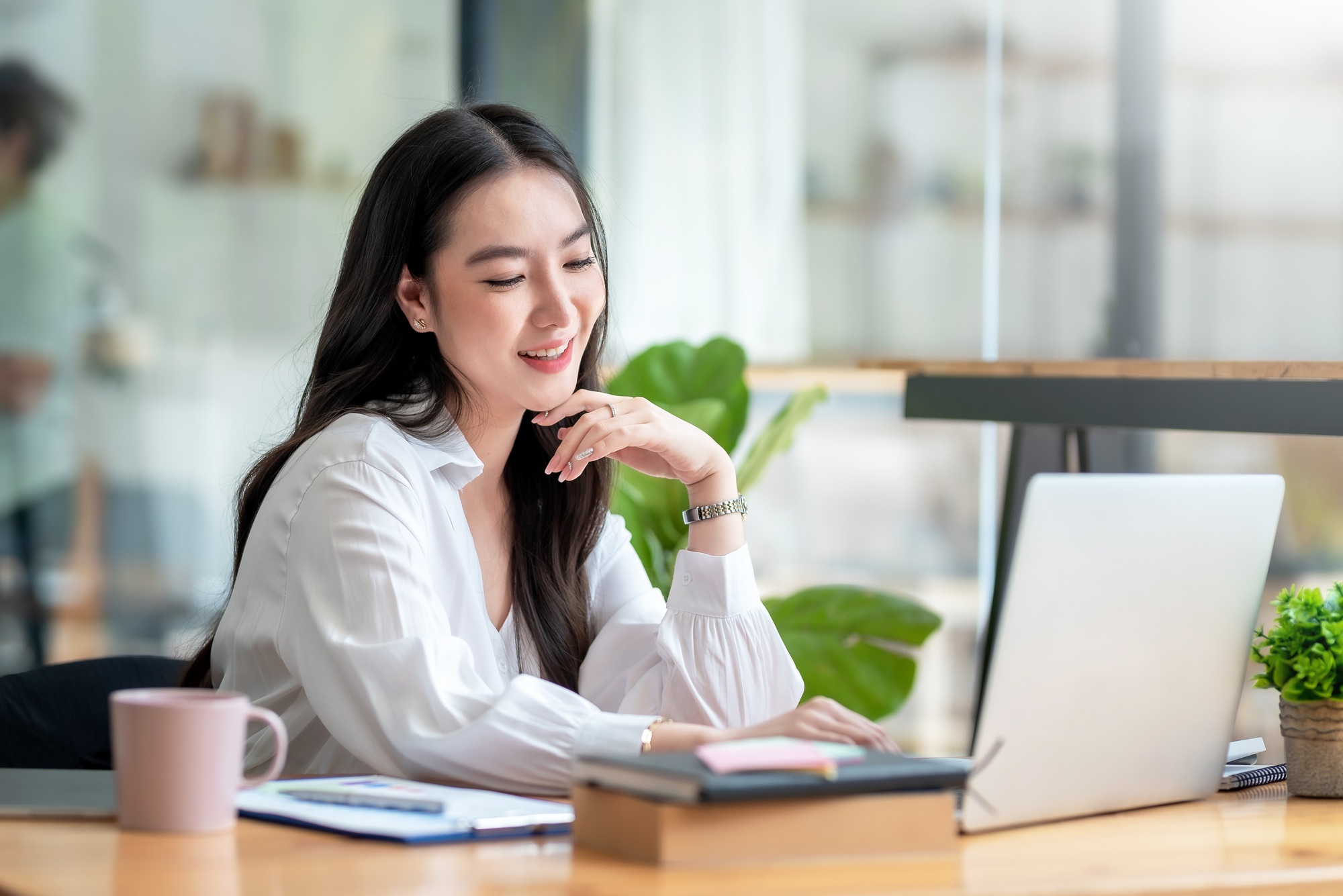 Portrait of smiling beautiful Asian businesswoman enjoy the idea sitting at office.