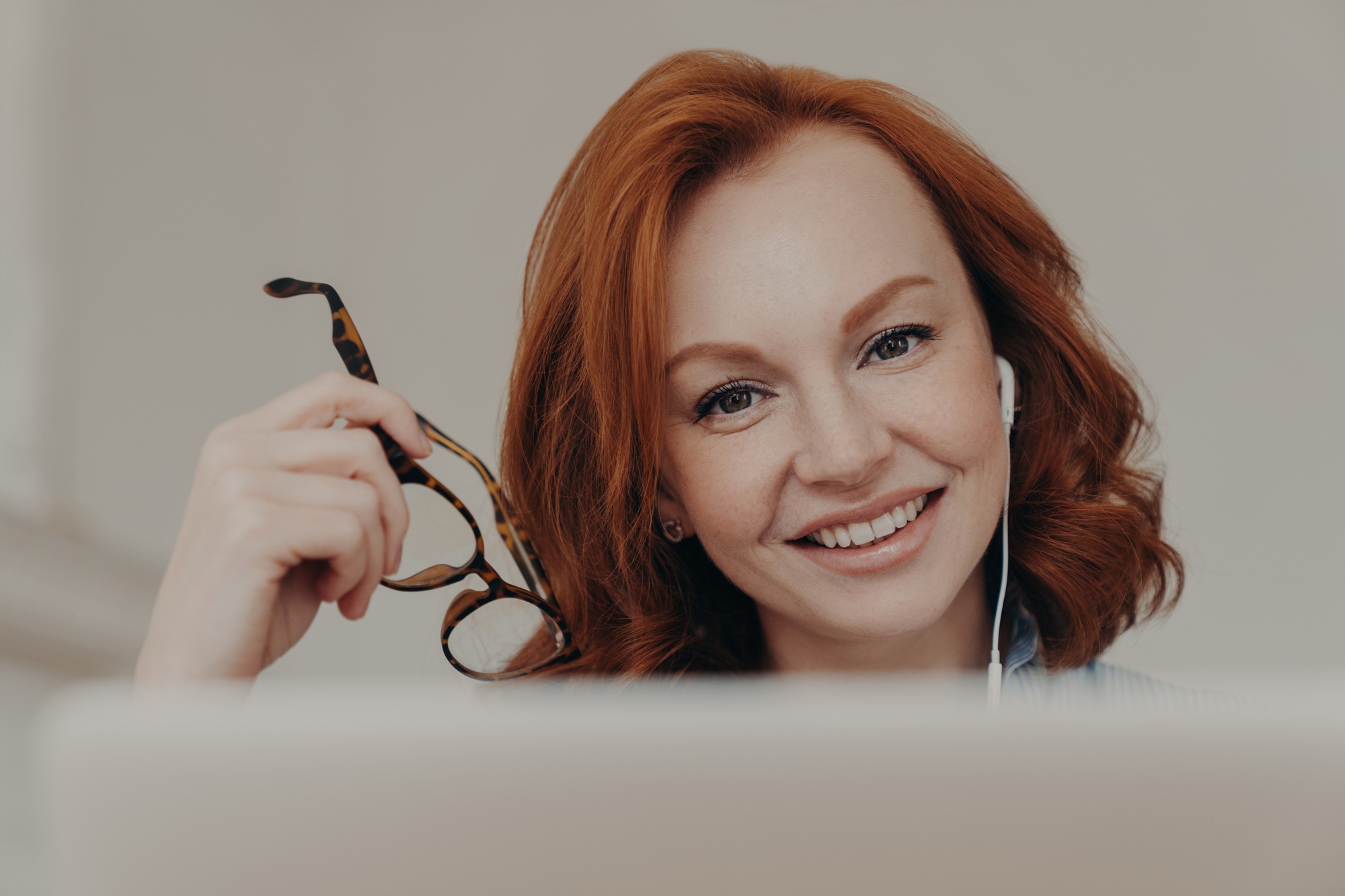 Positive woman smiles gently, enjoys online communication, watches tutorial webinar