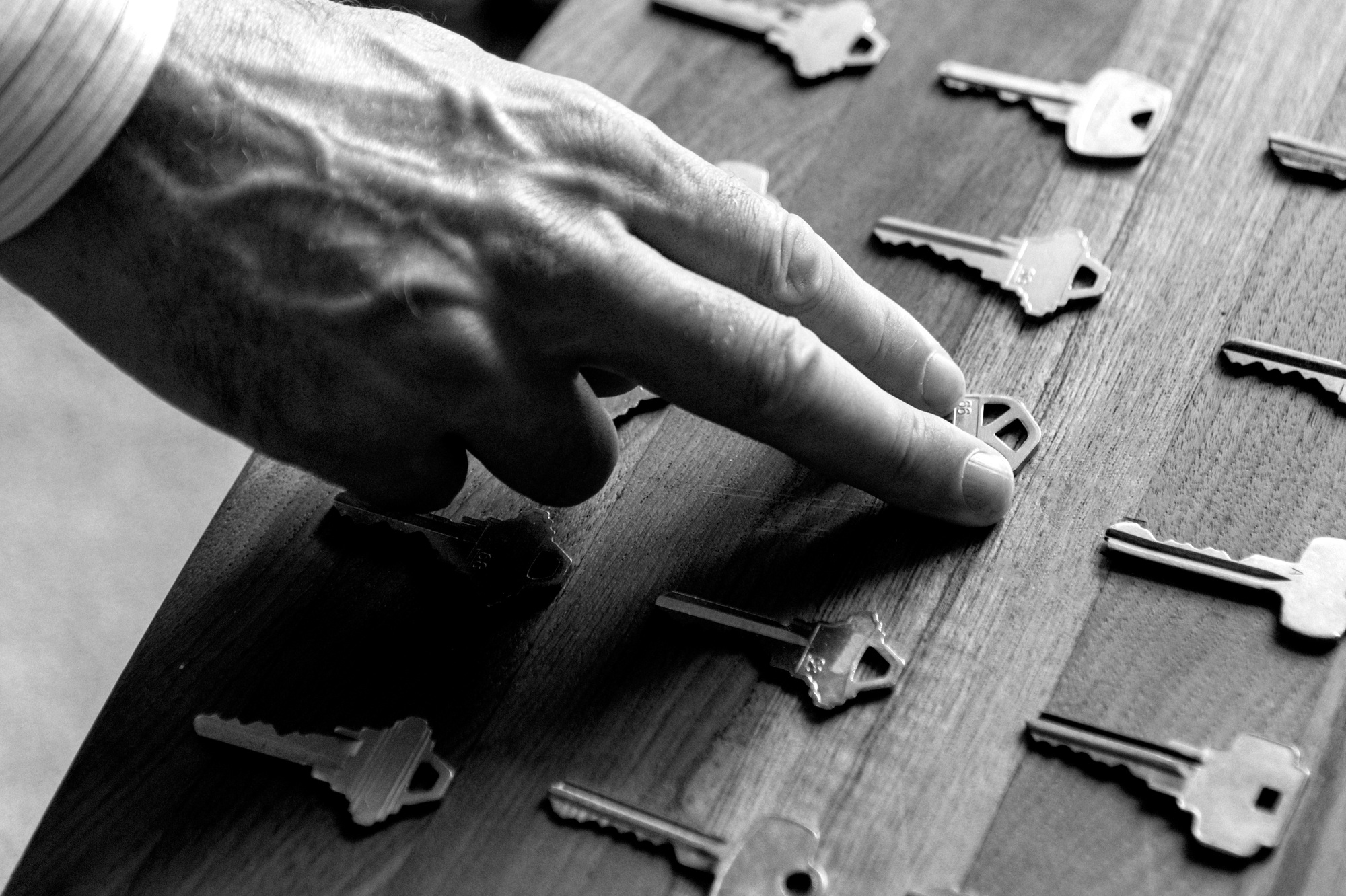 Real estate hand picking up a house key in black and white.