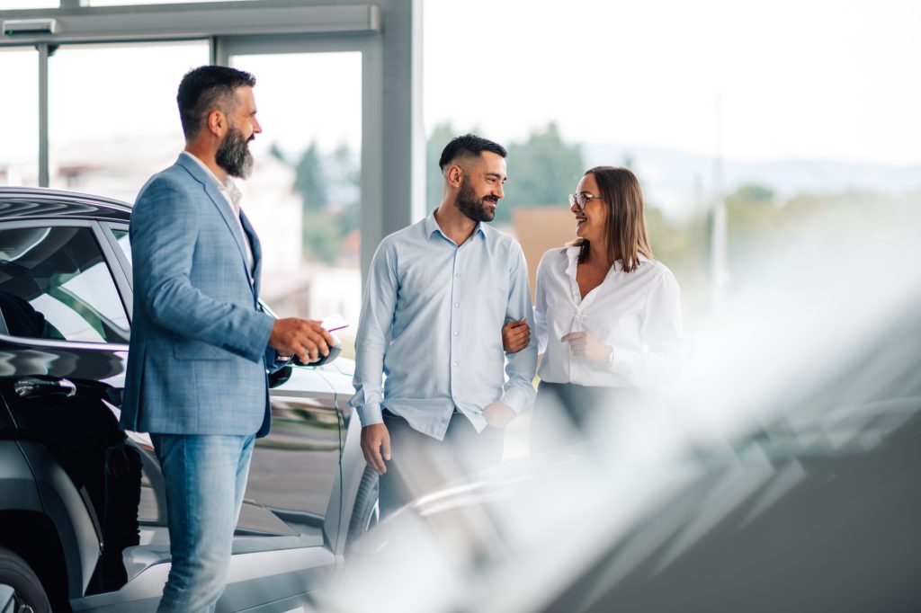 Sales agent assisting couple with car selection at dealership