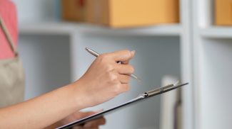 Small Business Management. A woman taking notes while checking inventory.