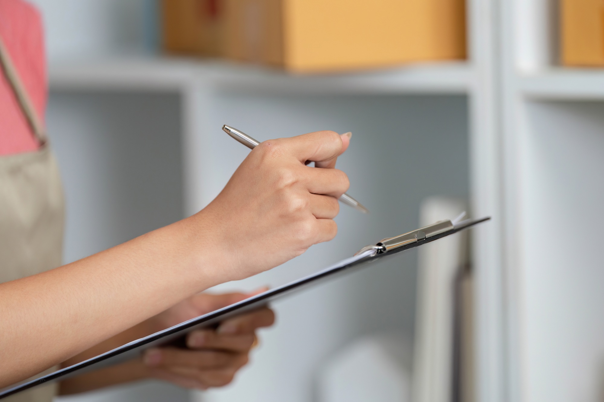 Small Business Management. A woman taking notes while checking inventory.