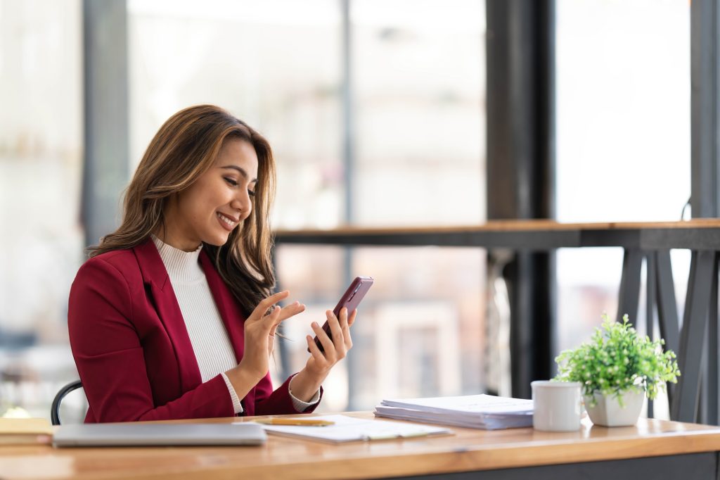Smiling beautiful Asian businesswoman analyzing chart and graph showing changes on the market and