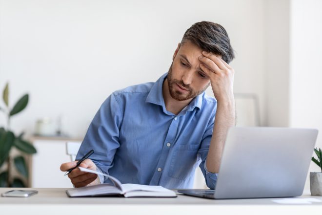 Tight Schedule. Tired Businessman Checking Business Appointments In Notepad At Office