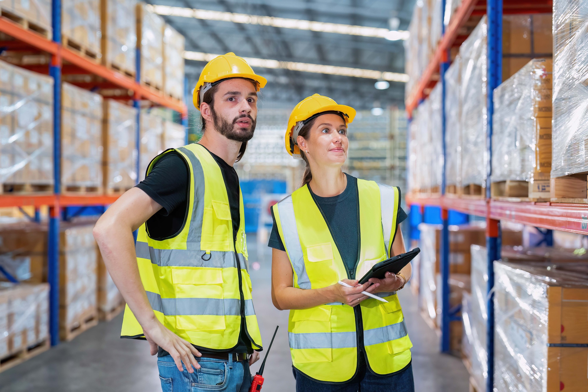 Warehouse worker standing check stock quantity of product and key information to tablet pc