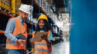Warehouse workers checking inventory using digital tablet and clipboard