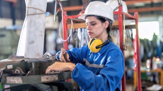 Woman in uniform working in machinery shop checking spare parts and wrench store in the tool box