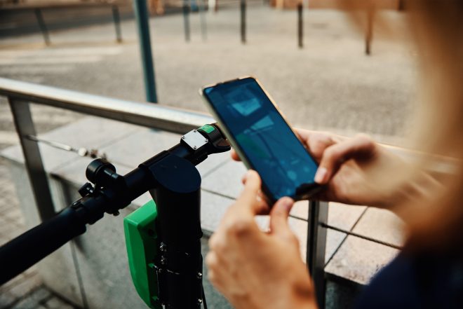 Woman unlock electric scooter for rent with a smartphone application