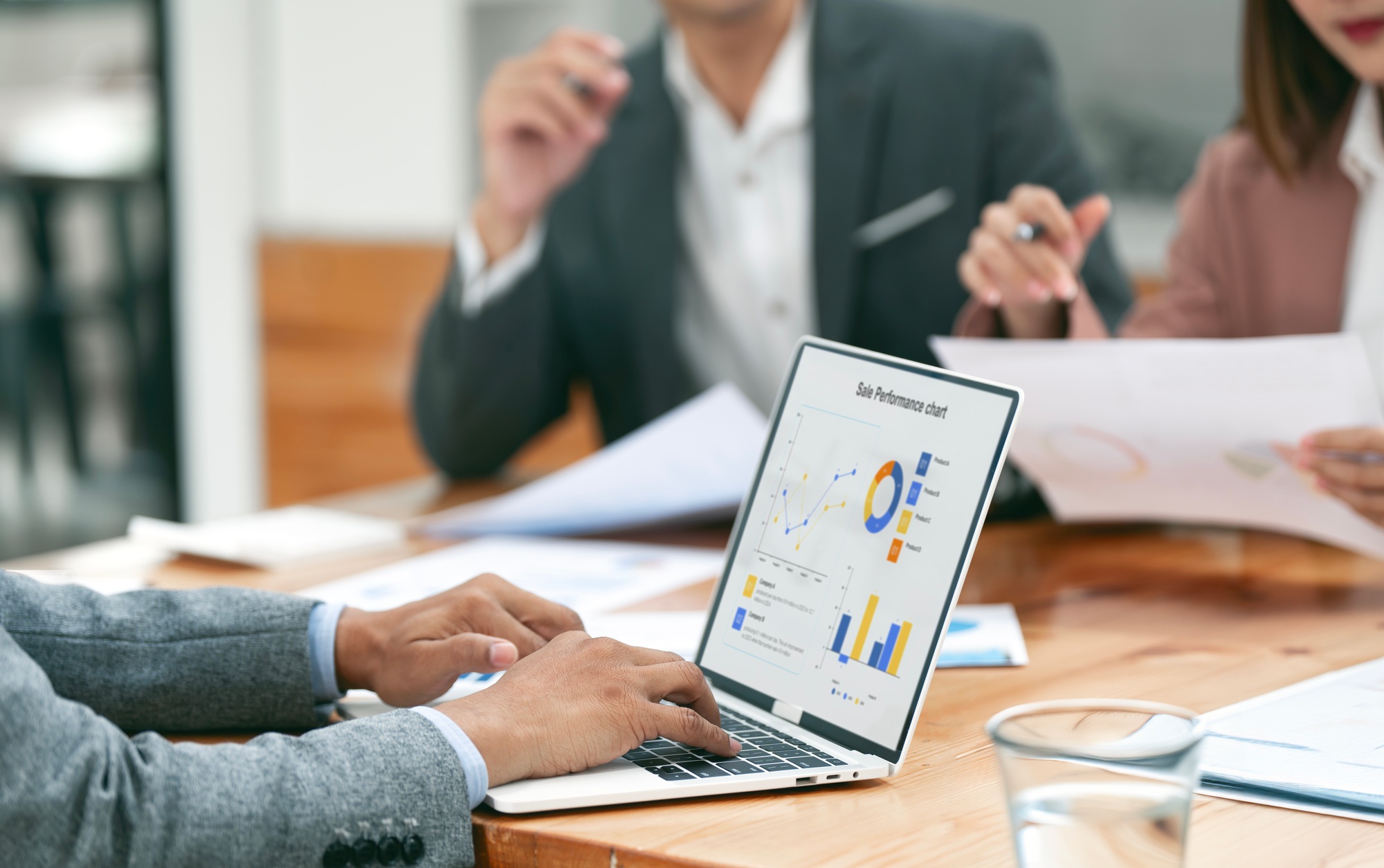 Young colleagues discuss business and analytical price charts using calculators and laptop
