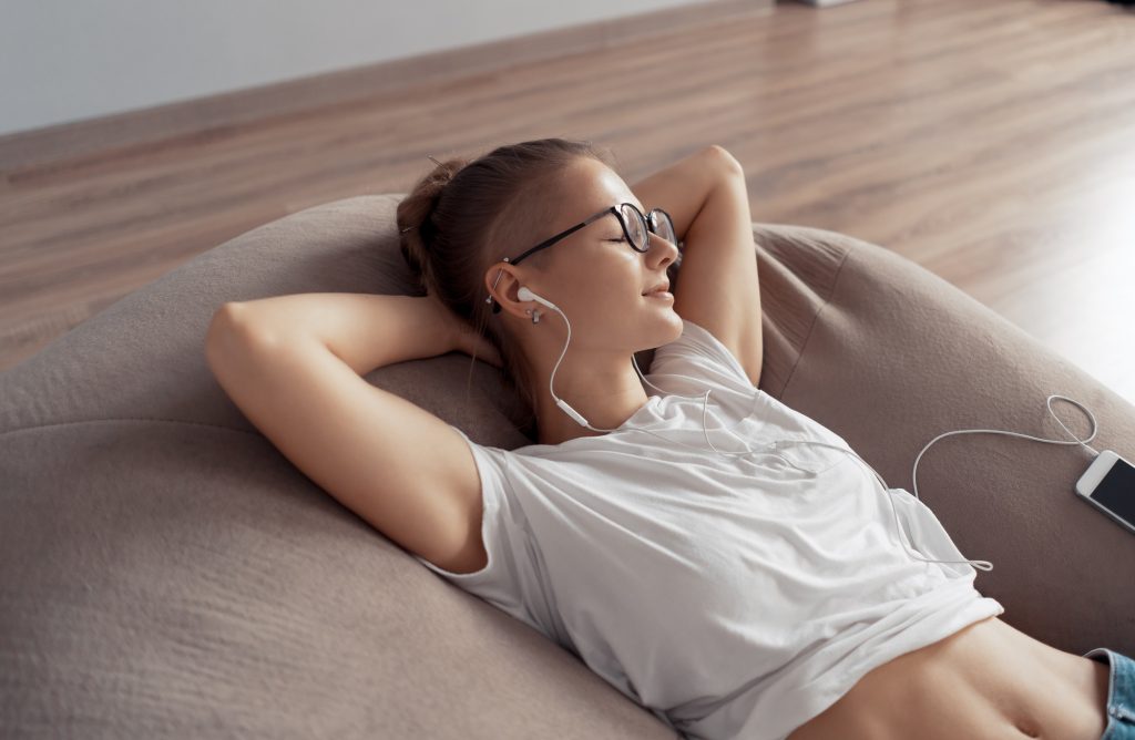Young girl is lying on a chair bag and listening to music from your phone
